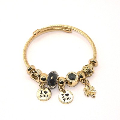 Ατσάλινο χρυσό βραχιόλι με μαύρη χάντρα και χρυσά κρεμαστά στοιχεία